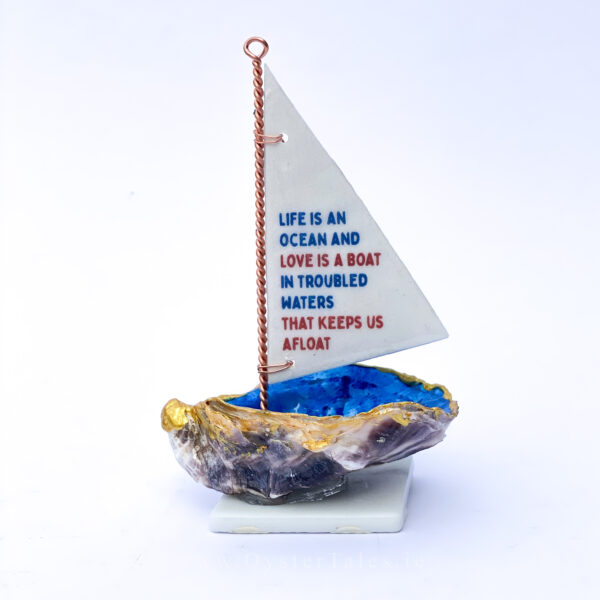 Life is an ocean and love is a boat in troubled waters that keeps us afloat. Oyster shell sailing boat ornament.
